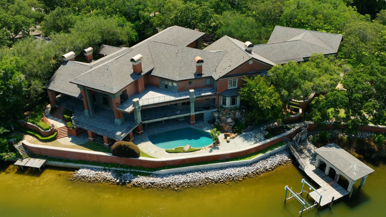 From above, the grandeur of 204 Laura Lane unfolds in full view — a sprawling brick estate seamlessly integrated into its lush, private setting on Pensacola Bay. The residence commands the shoreline with architectural distinction, featuring a resort-style pool, expansive terraces, and a boathouse that extends directly over the water. Mature trees surround the property, creating a sense of seclusion, while manicured landscaping and curved brick walls accentuate its elegance. From above, the grandeur of 204 Laura Lane unfolds in full view — a sprawling brick estate seamlessly integrated into its lush, private setting on Pensacola Bay. The residence commands the shoreline with architectural distinction, featuring a resort-style pool, expansive terraces, and a boathouse that extends directly over the water. Mature trees surround the property, creating a sense of seclusion, while manicured landscaping and curved brick walls accentuate its elegance.