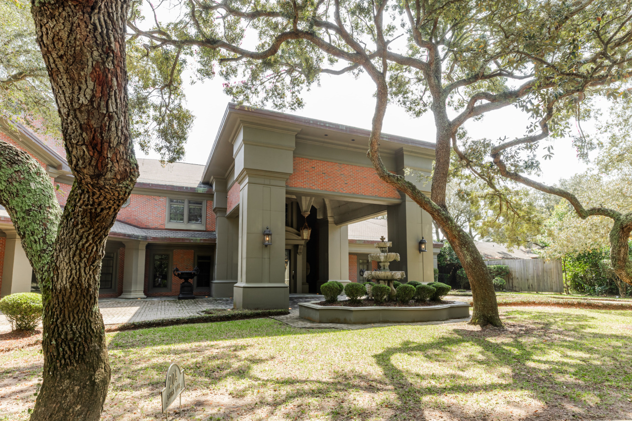The estate’s stately porte cochère, framed by mature oaks and accented with a tiered fountain, creates a dramatic and timeless arrival experience at 204 Laura Lane. The estate’s stately porte cochère, framed by mature oaks and accented with a tiered fountain, creates a dramatic and timeless arrival experience at 204 Laura Lane.