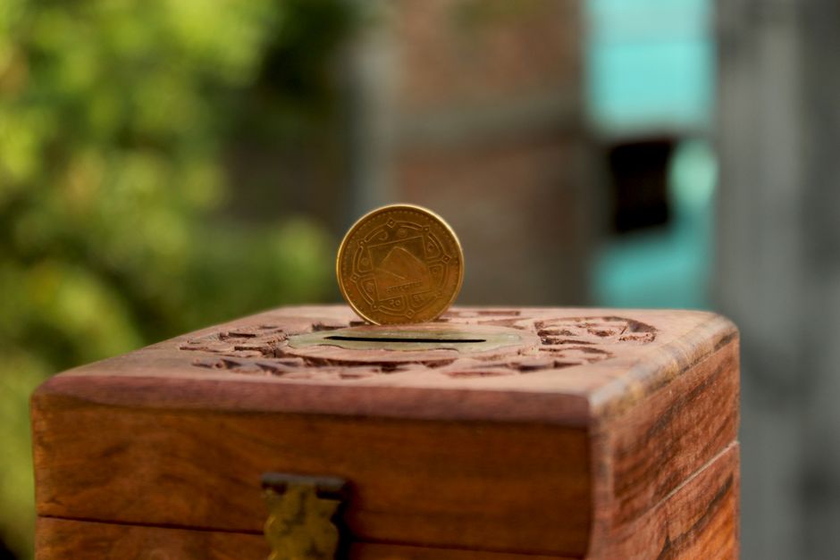 A minimalist photo of a house-shaped piggy bank with a single coin being dropped in, symbolizing the significant savings from a 1 percent real estate commission.
